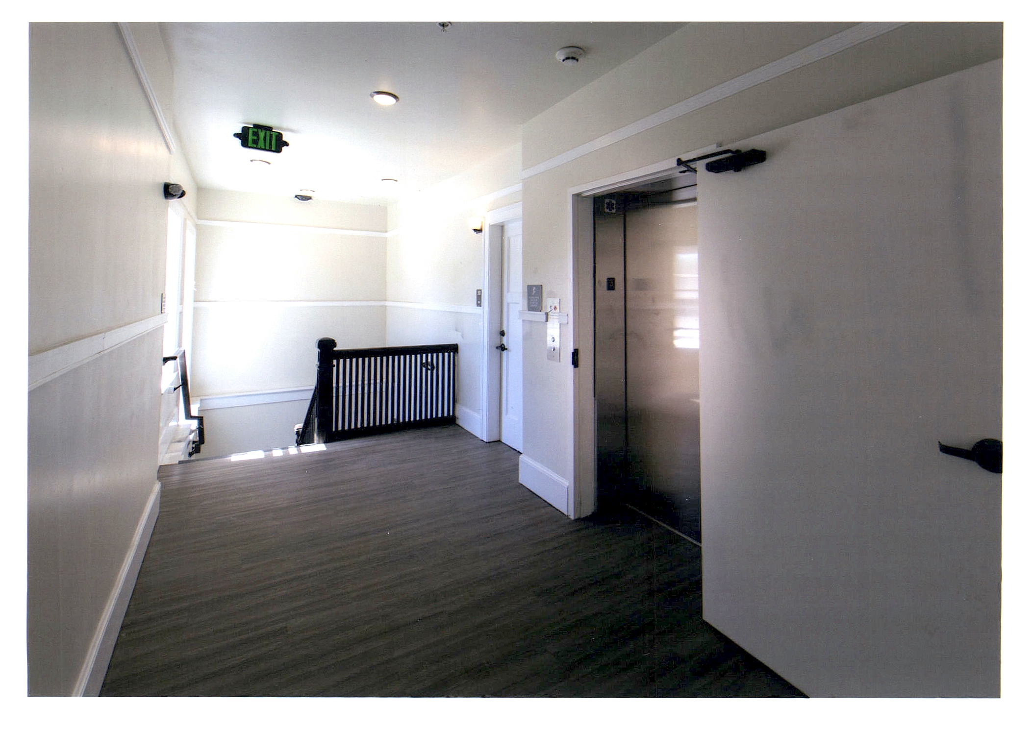 After: view of third floor hallway looking toward elevator and main stair.